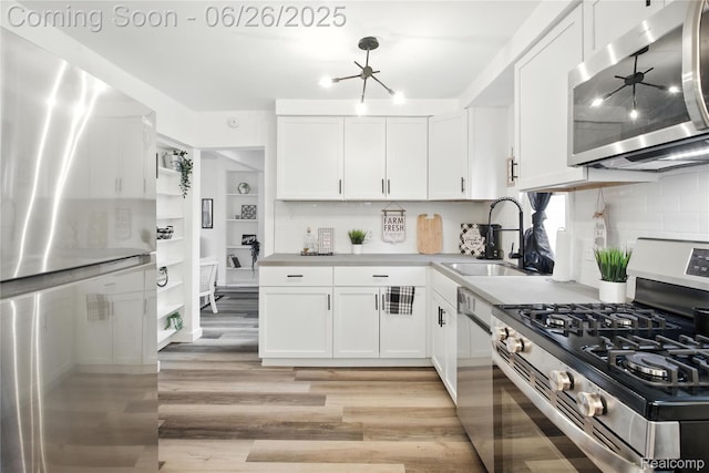8411 Hugh St, Westland, MI 48185 - kitchen with appliances with stainless steel finishes, light wood finished floors, white cabinets, and tasteful backsplash