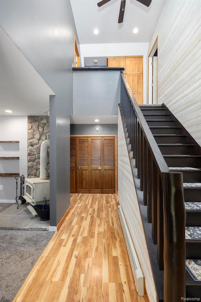 2931 N Lake Pleasant Rd, Attica, MI 48412 - stairway with a wood stove, a baseboard radiator, ceiling fan, wood finished floors, and recessed lighting