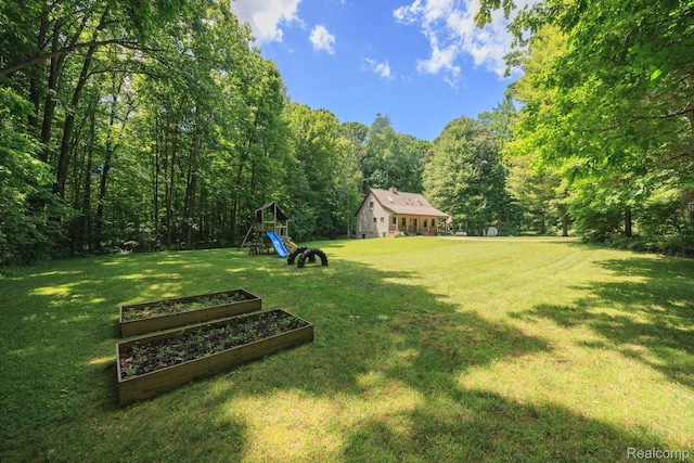 2931 N Lake Pleasant Rd, Attica, MI 48412 - view of grassy yard with a playground, a forest view, and a vegetable garden