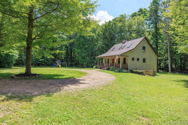 2931 N Lake Pleasant Rd, Attica, MI 48412 - view of front of home with covered porch, a playground, a chimney, a front lawn, and driveway