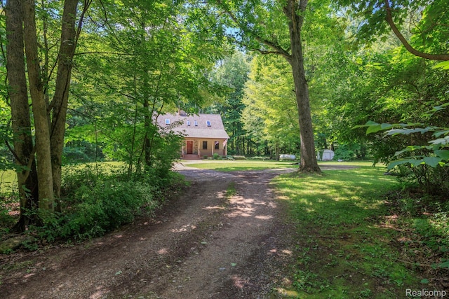 2931 N Lake Pleasant Rd, Attica, MI 48412 - view of front facade featuring a front yard, driveway, a storage unit, and a forest view