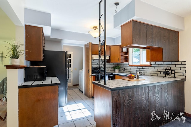 3541 Orshal Rd, Whitehall, MI 49461 - kitchen featuring black range with electric stovetop, a peninsula, decorative backsplash, tile countertops, and open shelves