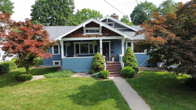 950 College Ave, Adrian, MI 49221 - bungalow with a chimney, covered porch, a front yard, and roof with shingles