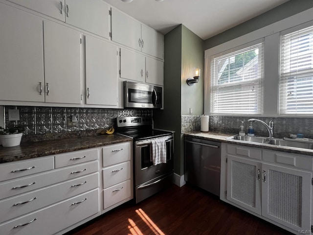 950 College Ave, Adrian, MI 49221 - kitchen with stainless steel appliances, decorative backsplash, dark wood-style flooring, white cabinets, and dark countertops
