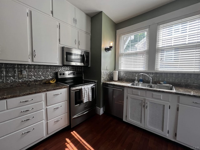 950 College Ave, Adrian, MI 49221 - kitchen featuring stainless steel appliances, decorative backsplash, dark wood finished floors, white cabinetry, and dark countertops