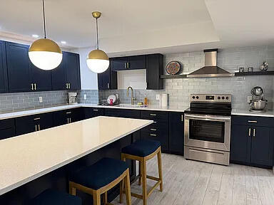 8255 Shady Brook Ln, Flushing, MI 48433 - kitchen featuring wall chimney range hood, stainless steel range with electric stovetop, a breakfast bar, and light countertops