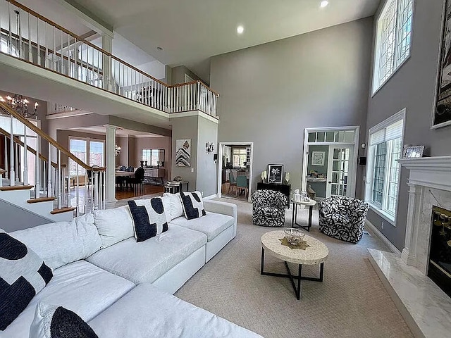 8255 Shady Brook Ln, Flushing, MI 48433 - carpeted living area featuring a premium fireplace, a towering ceiling, stairway, decorative columns, and a chandelier