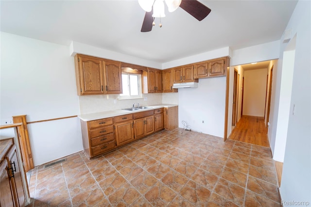 17213 Anne Ave, Detroit, MI 48101 - kitchen with under cabinet range hood, brown cabinets, ceiling fan, light countertops, and light stone finish flooring