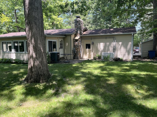 810 Oakgrove, Highland, MI 48356 - rear view of property with a chimney and a lawn