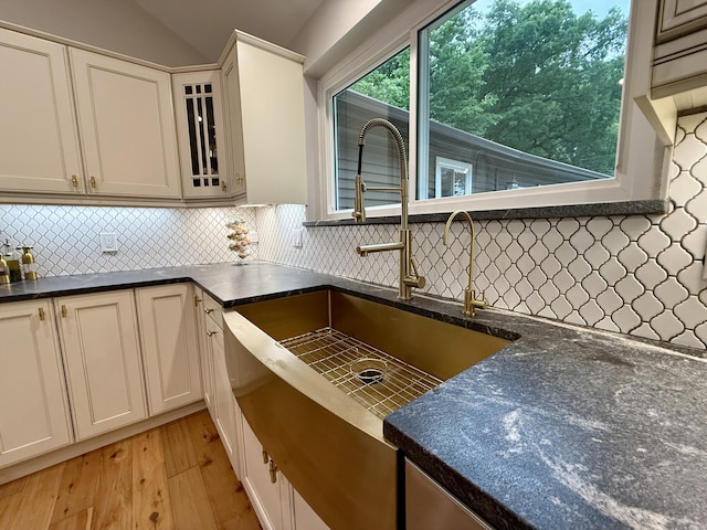 13955 Rattalee Lake Rd, Davisburg, MI 48350 - kitchen with dark countertops, light wood-type flooring, backsplash, glass insert cabinets, and lofted ceiling