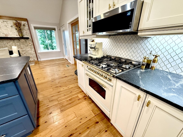 13955 Rattalee Lake Rd, Davisburg, MI 48350 - kitchen featuring stainless steel microwave, white gas range, light wood-type flooring, backsplash, and glass insert cabinets