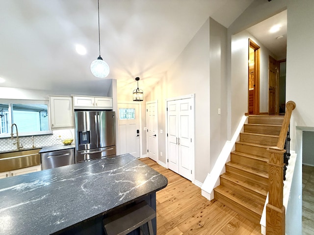 13955 Rattalee Lake Rd, Davisburg, MI 48350 - kitchen with appliances with stainless steel finishes, light wood finished floors, white cabinets, decorative backsplash, and hanging light fixtures