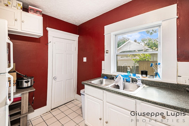 612 Norman St, Lansing, MI 48910 - kitchen with light tile patterned flooring, white cabinets, dark countertops, refrigerator, and a textured ceiling