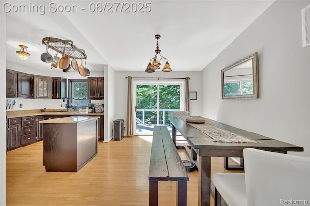 1522 Oregon Ct, Waterford, MI 48327 - kitchen featuring light wood-type flooring, dark brown cabinets, light countertops, a kitchen island, and lofted ceiling