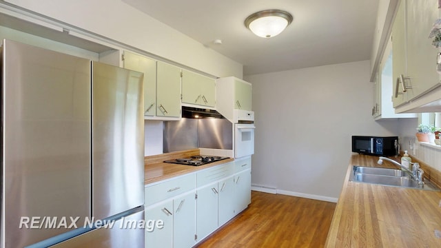 5071 Heidi Ln, Saginaw, MI 48604 - kitchen with black appliances, light wood-type flooring, under cabinet range hood, and decorative backsplash