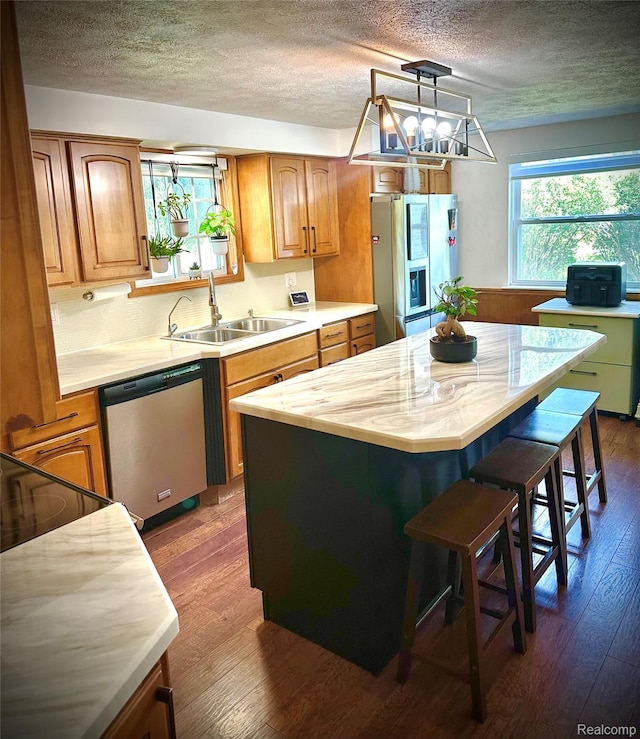 4502 E Wilkinson Rd, Owosso, MI 48867 - kitchen featuring appliances with stainless steel finishes, light countertops, a textured ceiling, a center island, and dark wood finished floors