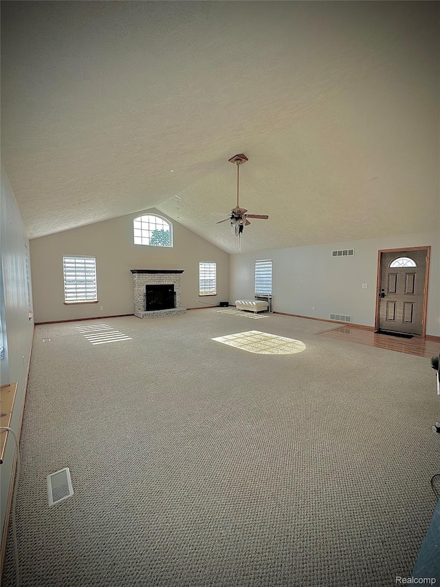4502 E Wilkinson Rd, Owosso, MI 48867 - unfurnished living room featuring lofted ceiling, a ceiling fan, carpet floors, plenty of natural light, and a fireplace with raised hearth