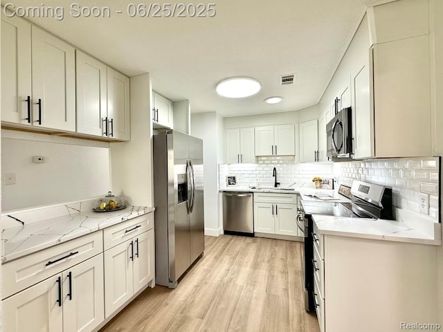 2526 Genes Dr, West Bloomfield, MI 48326 - kitchen featuring appliances with stainless steel finishes, light wood-type flooring, decorative backsplash, and white cabinetry