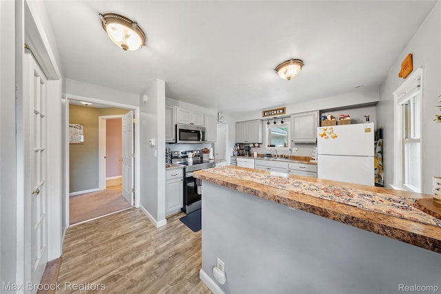 888 Mallock Rd, White Lake, MI 48386 - kitchen with appliances with stainless steel finishes, light wood finished floors, a peninsula, and light countertops