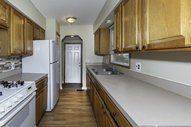 241 Dakota Ave, Ypsilanti, MI 48198 - kitchen with white gas range oven, dark wood-type flooring, decorative backsplash, brown cabinets, and arched walkways
