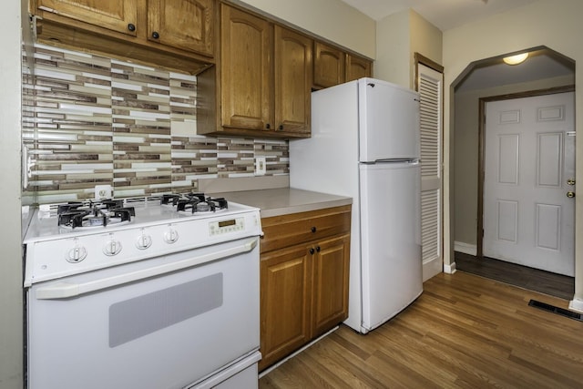 241 Dakota Ave, Ypsilanti, MI 48198 - kitchen featuring white appliances, decorative backsplash, brown cabinetry, and wood finished floors