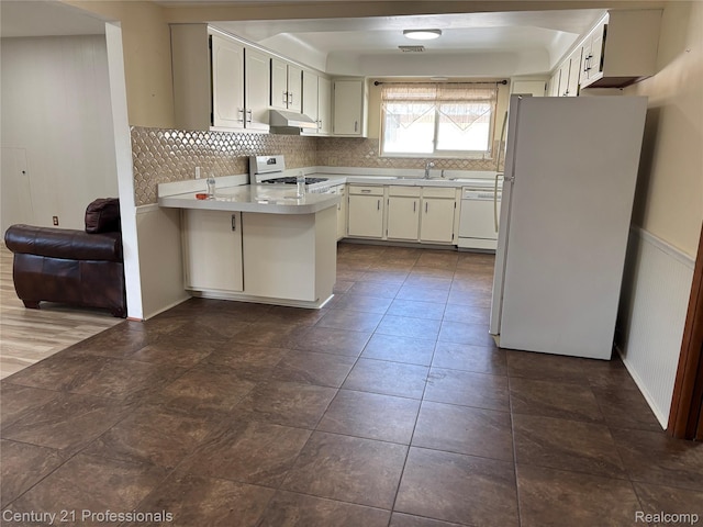 8105 Busch, Center Line, MI 48015 - kitchen featuring white appliances, under cabinet range hood, a peninsula, and backsplash