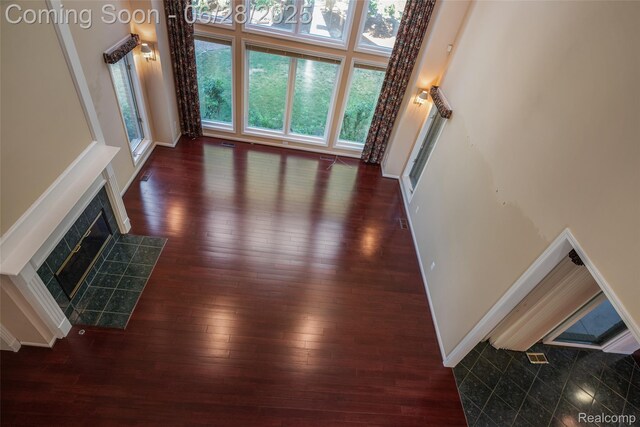 17601 Rolling Woods Cir, Northville, MI 48168 - unfurnished living room featuring wood-type flooring, a fireplace, and a high ceiling