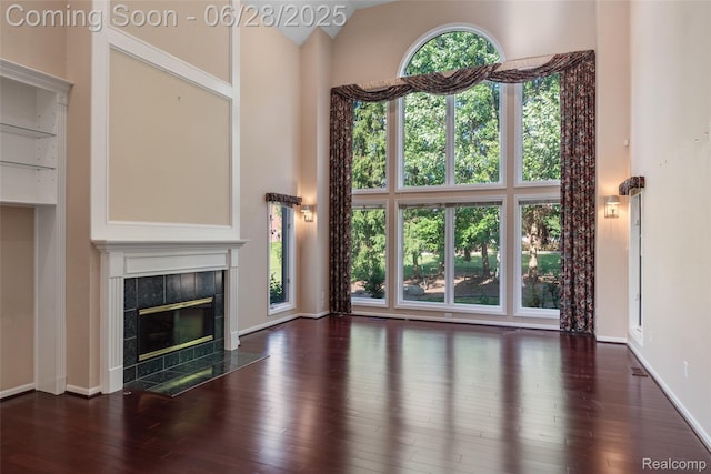 17601 Rolling Woods Cir, Northville, MI 48168 - unfurnished living room featuring a towering ceiling, a fireplace, and hardwood / wood-style flooring