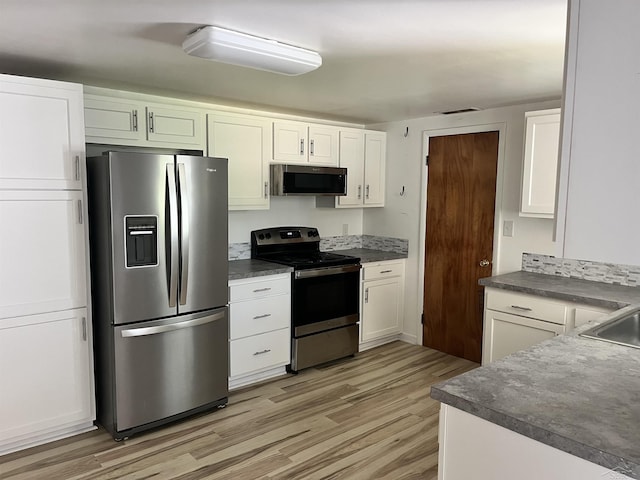 4704 Bishop St, Millington, MI 48746 - kitchen featuring stainless steel appliances, light wood-style flooring, dark countertops, and white cabinets