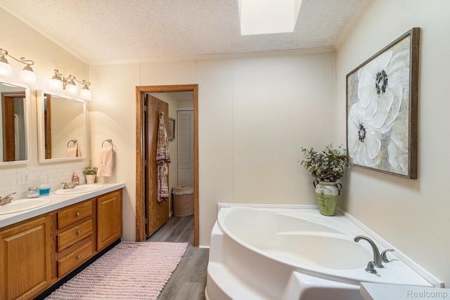13541 Austin Ct, Hartland, MI 48353 - full bath with double vanity, a garden tub, a textured ceiling, wood finished floors, and tasteful backsplash