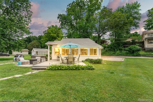11729 Algonquin Dr, Pinckney, MI 48169 - back of house at dusk featuring a lawn and a patio