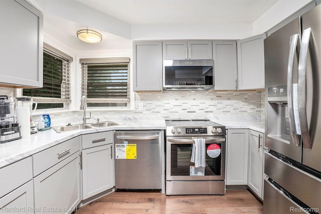 19100 Coral Gables St, Southfield, MI 48076 - kitchen with appliances with stainless steel finishes, gray cabinets, decorative backsplash, and light wood-style floors