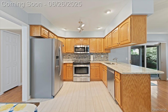 41615 Westmeath Cir, Clinton Township, MI 48038 - kitchen with appliances with stainless steel finishes, a peninsula, light stone counters, decorative backsplash, and light wood finished floors