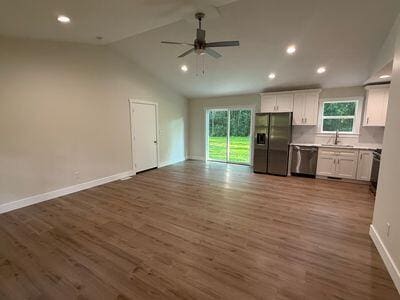 817 Sandow Rd, Midland, MI 48640 - kitchen with black fridge, open floor plan, stainless steel dishwasher, vaulted ceiling, and white cabinetry