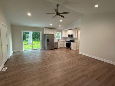 817 Sandow Rd, Midland, MI 48640 - kitchen featuring stainless steel appliances, open floor plan, ceiling fan, wood finished floors, and vaulted ceiling