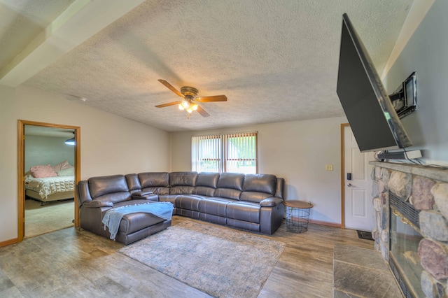 123 Carlysle Dr, Brooklyn, MI 49230 - living area with a textured ceiling, a ceiling fan, wood finished floors, and a stone fireplace