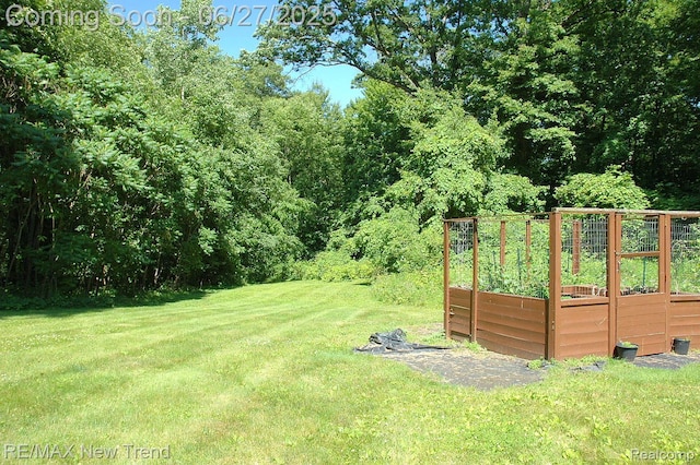 785 Pathway Dr, Howell, MI 48843 - view of grassy yard featuring a vegetable garden and a view of trees