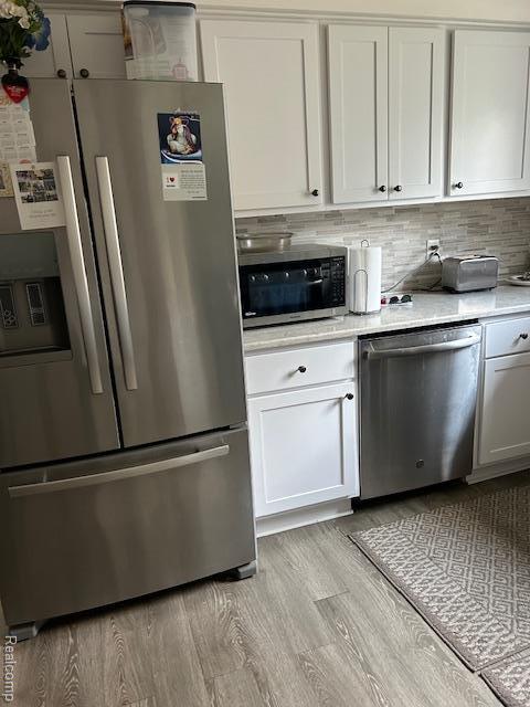 20796 Gill Rd, Farmington Hills, MI 48335 - kitchen with appliances with stainless steel finishes, light countertops, light wood finished floors, white cabinetry, and tasteful backsplash