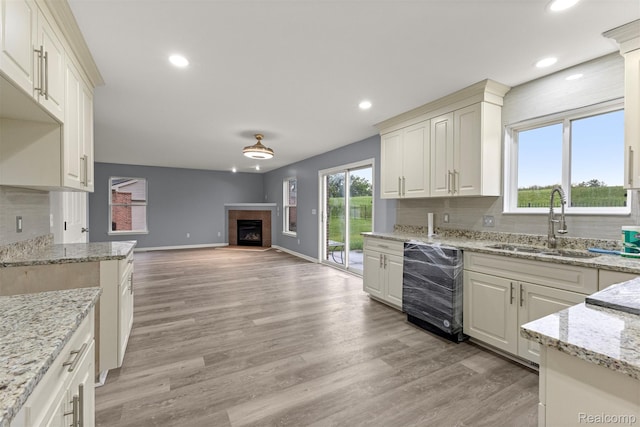 10913 Edlie Cir, Dearborn Heights, MI 48214 - kitchen featuring dishwasher, a tiled fireplace, recessed lighting, open floor plan, and light stone counters