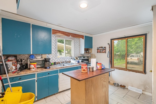 735 W Stewart St, Owosso, MI 48867 - kitchen with tasteful backsplash, blue cabinets, ornamental molding, light tile patterned flooring, and a kitchen island