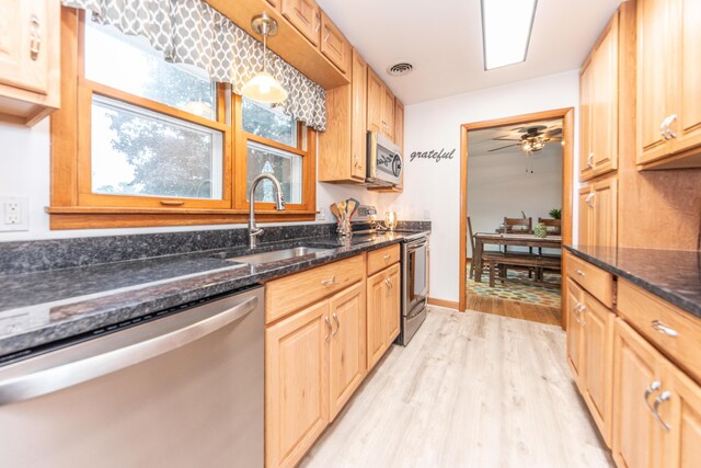 1169 Wilbur, Pinckney, MI 48169 - kitchen featuring appliances with stainless steel finishes, light wood finished floors, dark stone counters, ceiling fan, and light brown cabinets