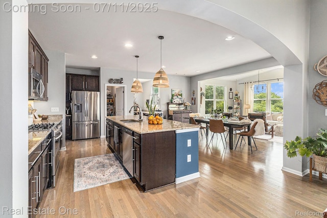 59141 Peters Barn Dr, South Lyon, MI 48178 - kitchen featuring stainless steel appliances, dark brown cabinets, arched walkways, light wood finished floors, and pendant lighting