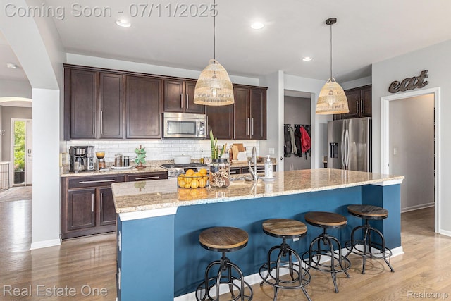 59141 Peters Barn Dr, South Lyon, MI 48178 - kitchen with stainless steel appliances, light wood-type flooring, dark brown cabinetry, tasteful backsplash, and recessed lighting