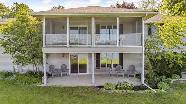 38 Evans Trl, Tipton, MI 49287 - back of house with a patio area, a lawn, a shingled roof, and a sunroom