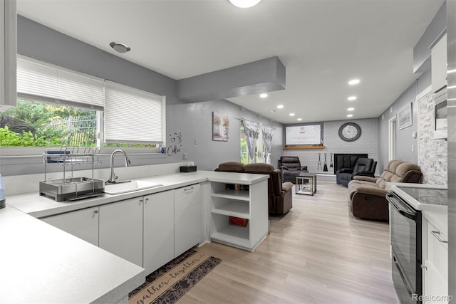2738 Berry Dr, Bloomfield Hills, MI 48304 - kitchen with black electric range oven, white cabinets, light countertops, a peninsula, and light wood-style floors