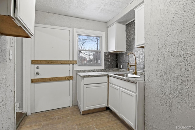 9110 Mansfield St, Detroit, MI 48228 - kitchen with wood finished floors, white cabinets, backsplash, and a textured ceiling
