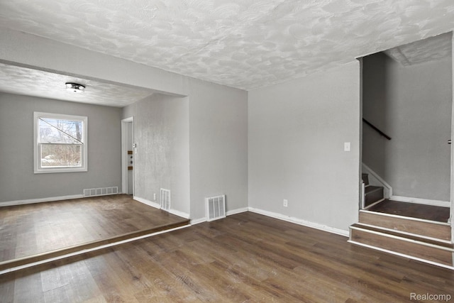 9110 Mansfield St, Detroit, MI 48228 - unfurnished living room featuring a textured ceiling, wood finished floors, and stairway