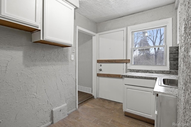 9110 Mansfield St, Detroit, MI 48228 - kitchen with white cabinets, wood finished floors, and a textured ceiling