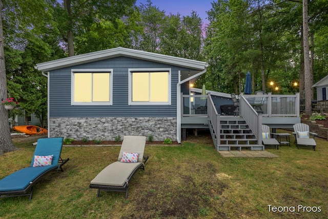 12865 S Englewright Dr, Sand Lake, MI 49343 - back of house at dusk featuring a deck, a yard, and stairway