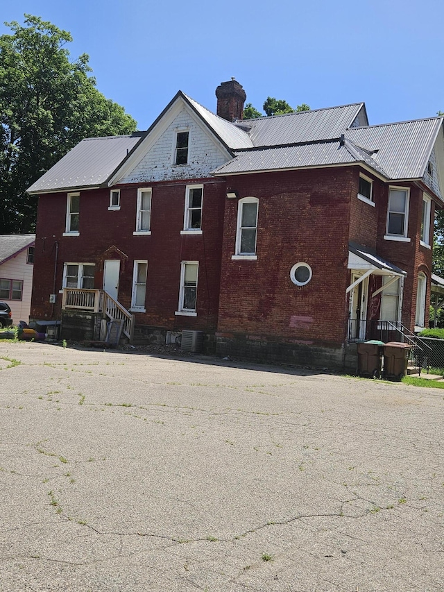 702 N Superior St, Albion, MI 49224 - view of side of property featuring brick siding, a metal roof, and a chimney